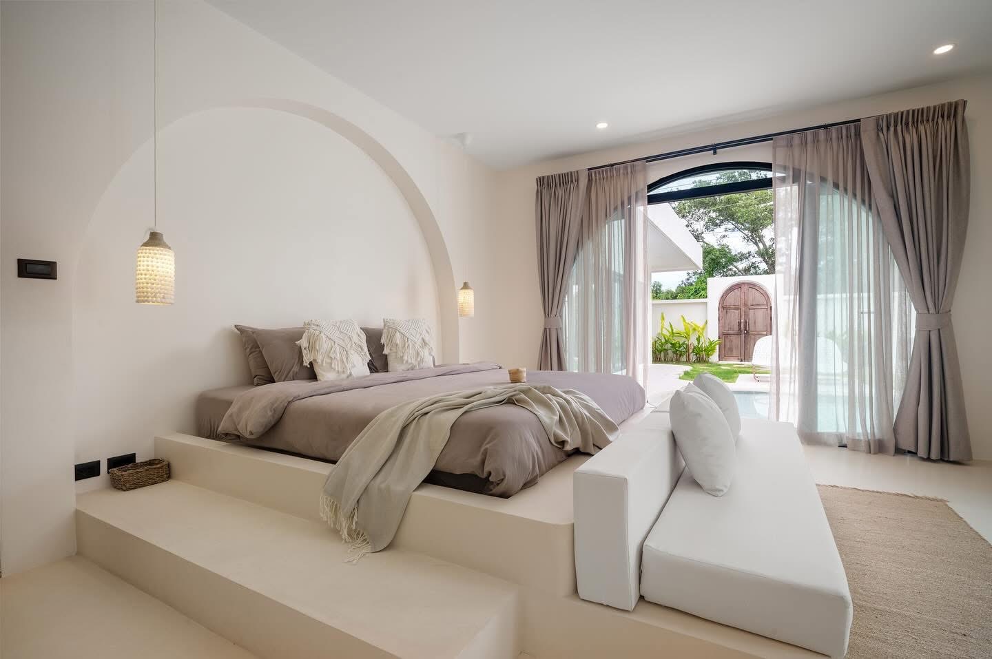 Villa Kyma bedroom with soft neutral finishes and arched garden doors